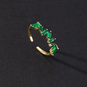 Macro shot of gold-plated snake ring featuring emerald green cubic zirconia stones
