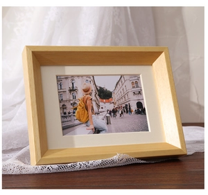 Detail of solid wood photo frame with natural grain and white mat on wooden desk