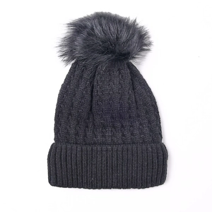 Women's black cable knit beanie with a large faux fur pompom and ribbed cuff