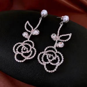 Silver needle flower earrings with pearls and rhinestones on elegant silk background
