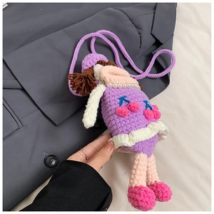 Close-up of handmade purple crochet girl crossbody bag with cherry dress and pearl chain
