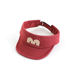 Close-up detail of a red children's sun visor with a beige M letter patch and stitching.