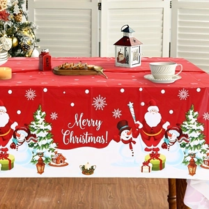 Detail of a festive Christmas tablecloth with Santa and snowman patterns on a red table