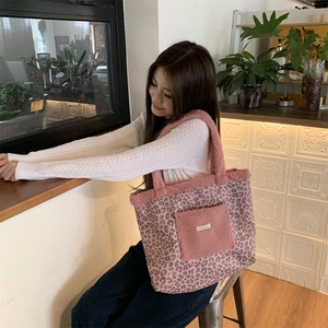 Detail of pink leopard print plush tote bag with fleece pocket and branded label