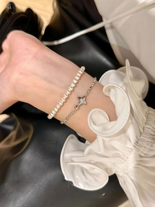 Detailed view of elegant star pendant bracelet and white pearl set worn on wrist