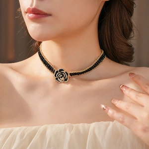 Close-up of a floral necklace featuring black beads and a diamond-encrusted flower pendant