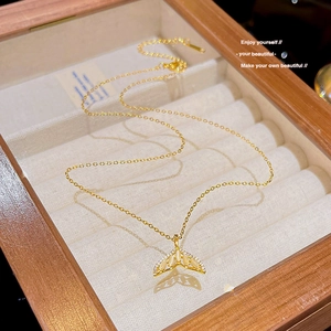 Detail of 18K gold fishtail pendant with gemstones in a luxury velvet jewelry box