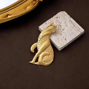 Vintage golden cat brooch with relief texture on textured surface and beige stone
