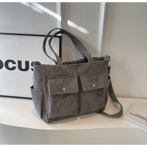 Detail of grey corduroy tote bag with dual front snap pockets and adjustable strap