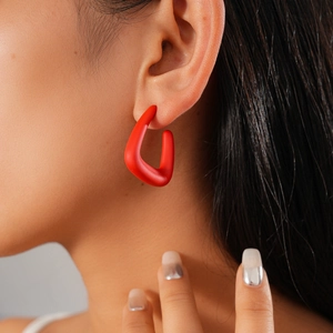 Close-up of matte red acrylic C-shaped earring on model showing sleek geometric design