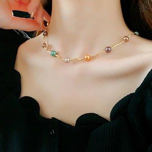Close-up of golden wave pearl necklace with multicolor beads on a model neck
