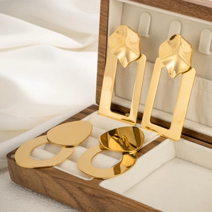Detailed view of geometric gold stainless steel earrings set in a wooden jewelry box