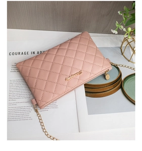 Détail d'un sac bandoulière matelassé rose avec chaîne dorée sur un magazine chic