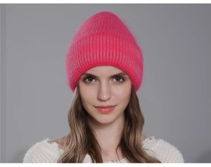 Close-up of bright pink thick knit rabbit fur hat with fluffy texture for winter warmth