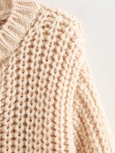 Macro shot of the beige chunky knit sweater texture and round neckline detail