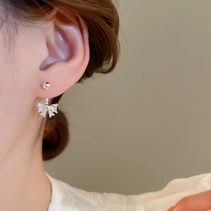 Elegant silver bow earrings with sparkling cubic zirconia shown on model's ear