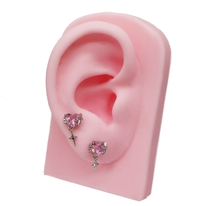 Detail of pink heart zircon ear stud with a hanging silver star on a silicone ear model