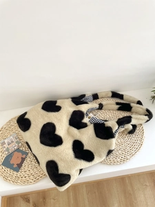 Detail of plush heart tote bag with blue checkered lining on straw mat background