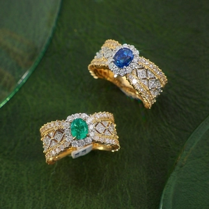 Macro shot of luxury vintage emerald and sapphire rings with ornate gold lacework and diamonds
