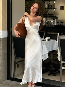 Elegant white satin maxi dress with deep V-neck and lace trim for a luxury resort look
