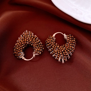 Détail de boucles d'oreilles cœur en perles de cristal bronze sur tissu satiné