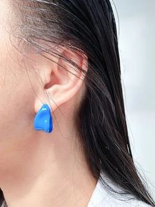 Close-up of model wearing an irregular blue geometric enamel earring with a high-gloss finish