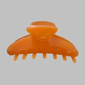 Detail view of large orange acetate hair claw clip with glossy finish and strong grip teeth