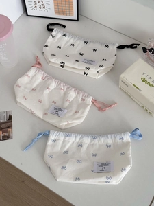 Close-up of three drawstring storage bags with black, pink, and blue bow patterns