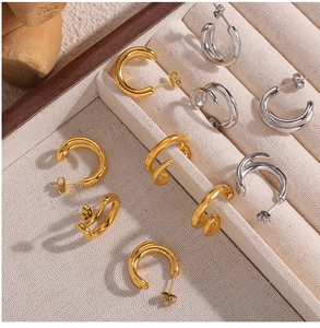 Detailed view of double-layer C-shaped gold and silver earrings in a beige jewelry box