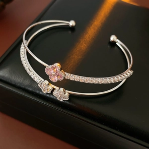 Macro view of double-layer silver bracelet featuring pink zircon four-petal flowers