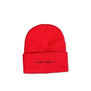 Gros plan d'un bonnet en maille rouge avec broderie freedom cursive et texture côtelée
