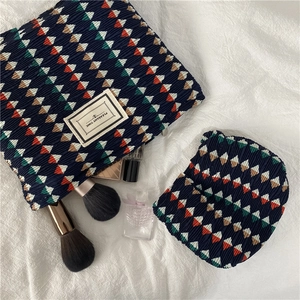 Detail of pleated geometric cosmetic bags set with 'PLEASANT TIME' fabric label
