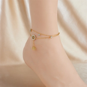 Double-layered gold anklet with tree of life charm and teardrop crystals on silk background