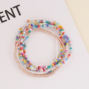 Bohemian multilayer seed bead and crystal tassel bracelet with gold accents on white base