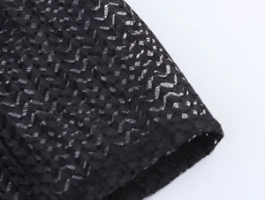 Detailed macro view of black mesh fabric showing intricate hollowed-out lace texture