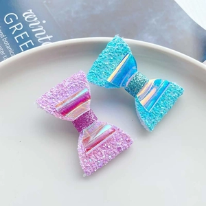 Close-up of pink and blue glittery hair clips with iridescent center on a white plate