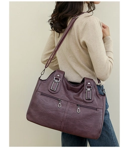 Detail view of large purple soft leather tote bag with dual zippers and crossbody strap