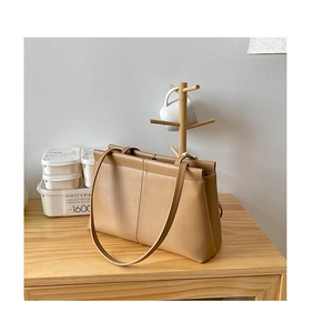 Detail of minimalist khaki PU leather tote bag on a light wooden table surface