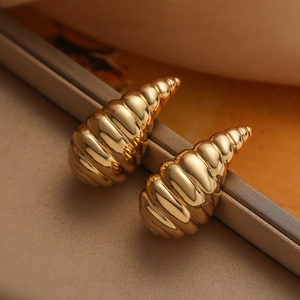 Elegant gold spiral water drop stud earrings with polished texture in jewelry box