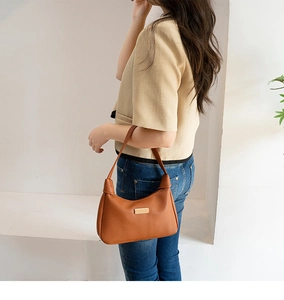 Caramel brown pebbled leather crescent underarm bag with gold metal plaque detail