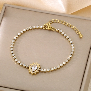 Close-up of gold chain bracelet with oval white zircon and heart charm on satin