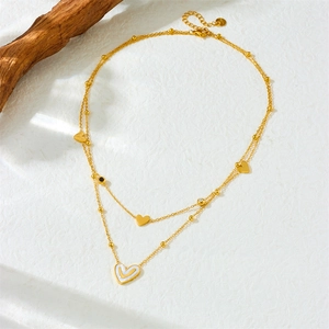 Double-layered gold stainless steel heart necklace with white shell pendant on textured paper