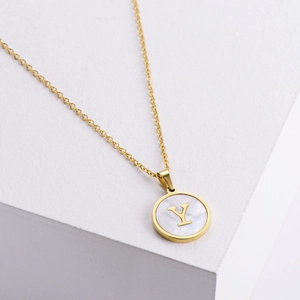Detalle de collar de oro de 18k con colgante redondo de nácar y la letra Y