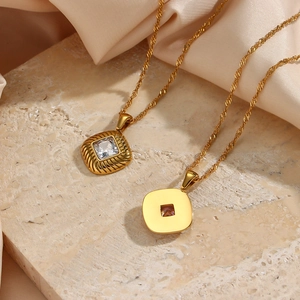 Macro detail of gold geometric pendants with zircon stones on stone and satin background