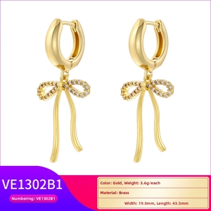 Detailed view of gold plated brass bow earrings with white sparkling crystal accents
