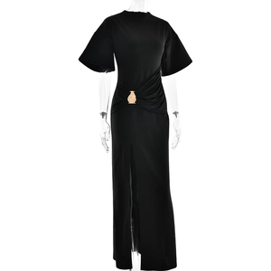Dettaglio di un elegante abito lungo nero con fibbia dorata e spacco laterale sulla gonna