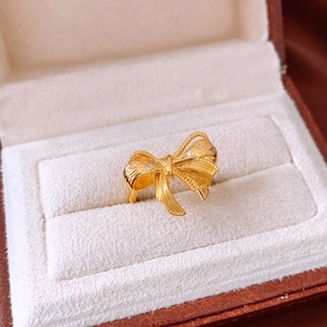 Macro shot of gold ribbon bow ring with micro-pave crystals in a velvet gift box