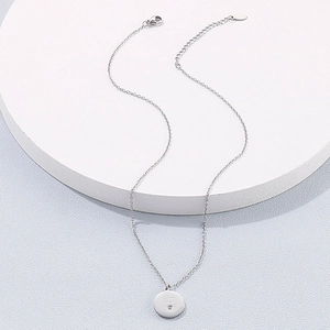 Gros plan du pendentif pièce en acier inoxydable argenté avec gravure Good Luck sur socle