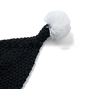 Detail of black chunky knit hat featuring a large white fluffy pom-pom top decoration