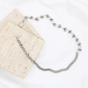 Silver Cuban link necklace with knot design and OT toggle clasp on beige stone